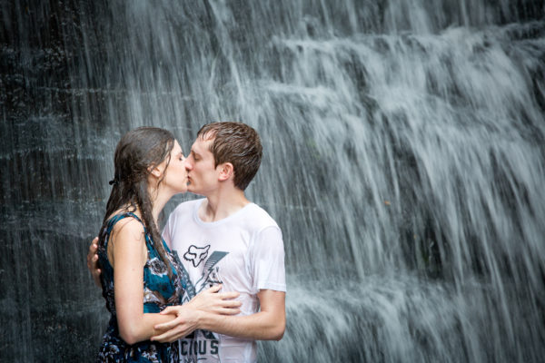 Kissing in front of a waterfall for their engagement shoot